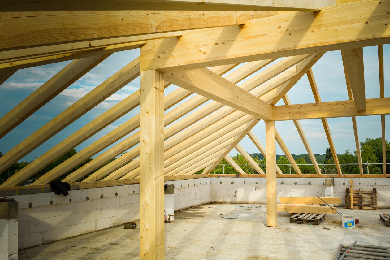 Timber roof framing under construction against a blue sky